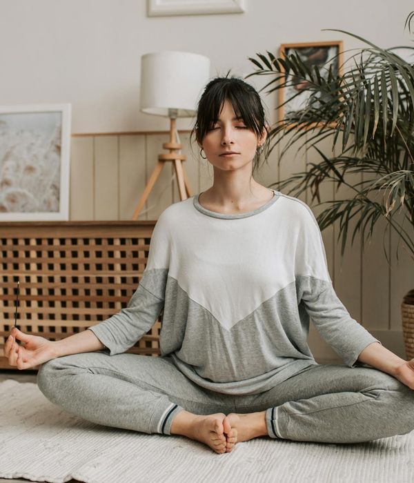 Woman in a calm yoga pose in a dark room with a warm light.